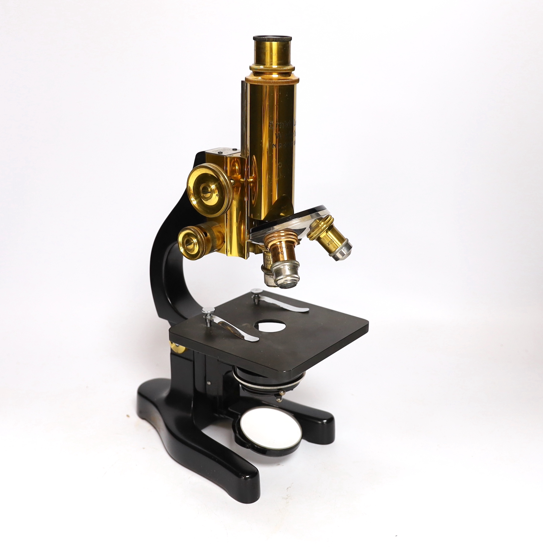 An early 20th century Leitz microscope in a teak case, with alternative lenses, card inserts and sliding compartment with glass slides, matching serial numbers stamped onto case and on magnification table